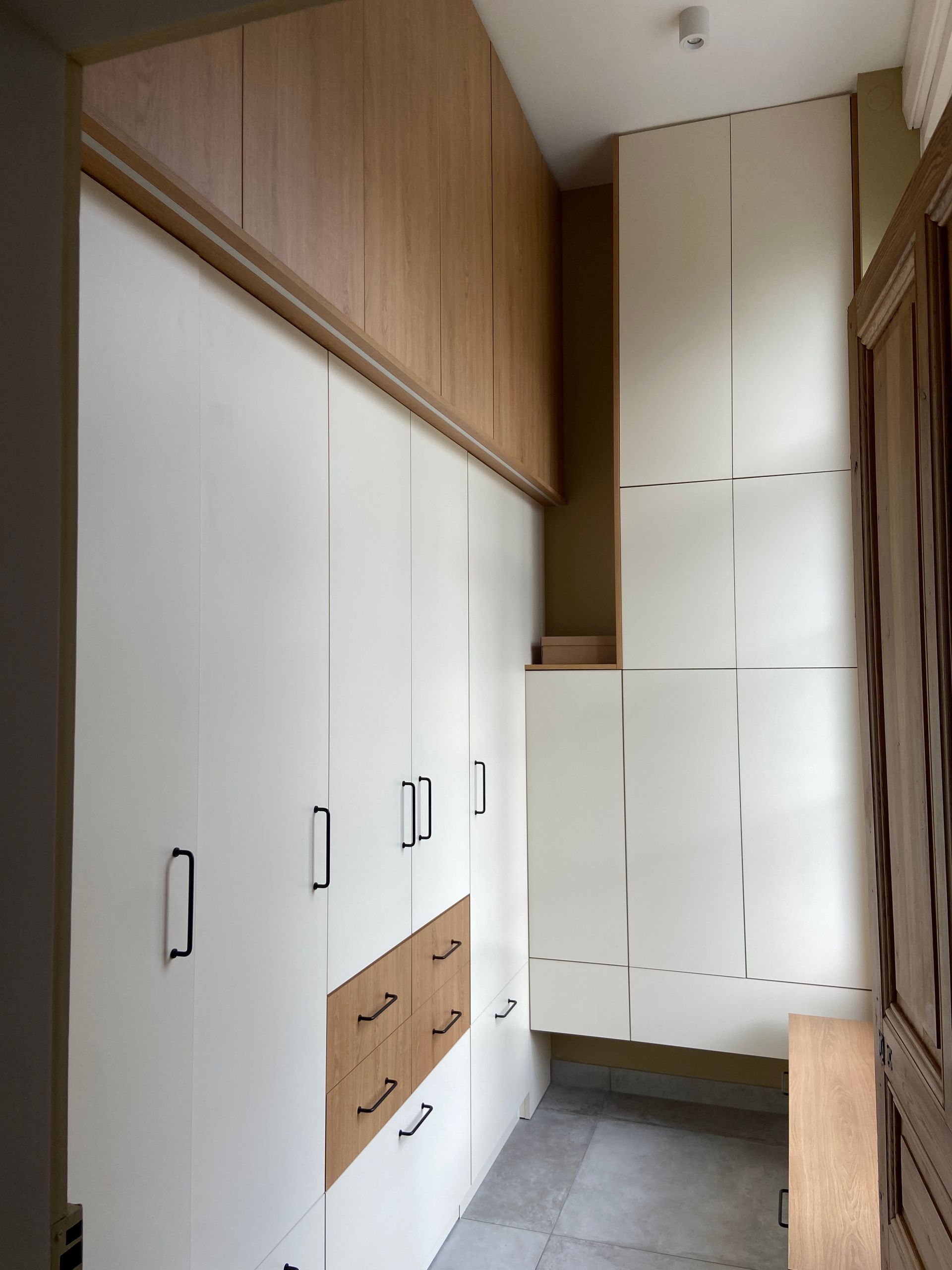 Placard intégré avec armoires, tiroirs et rangements en hauteur blancs et en bois.