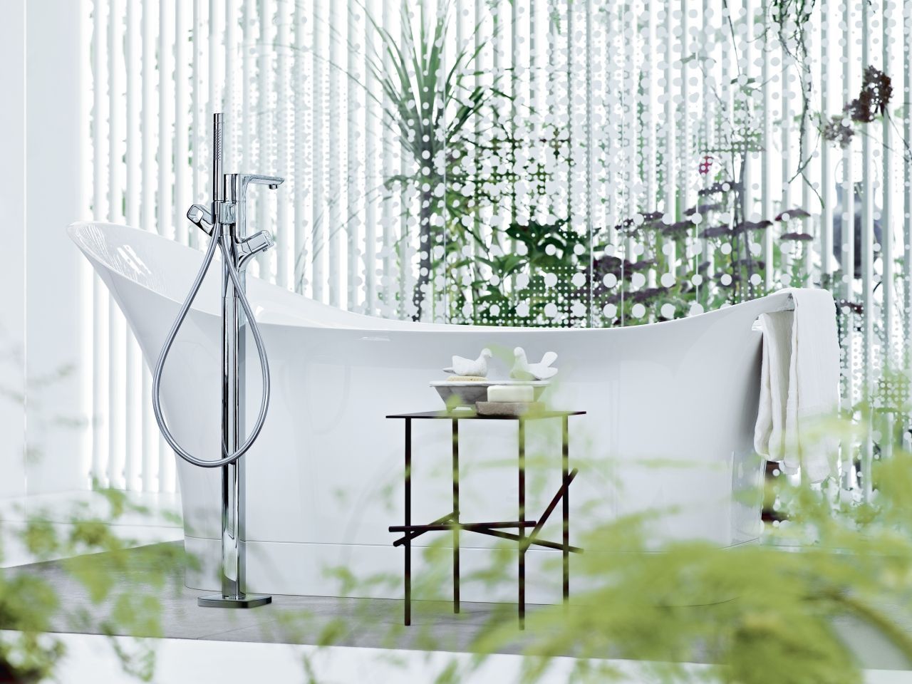 Baignoire blanche près de la fenêtre avec plantes. Robinet chromé, table d'appoint décorative.