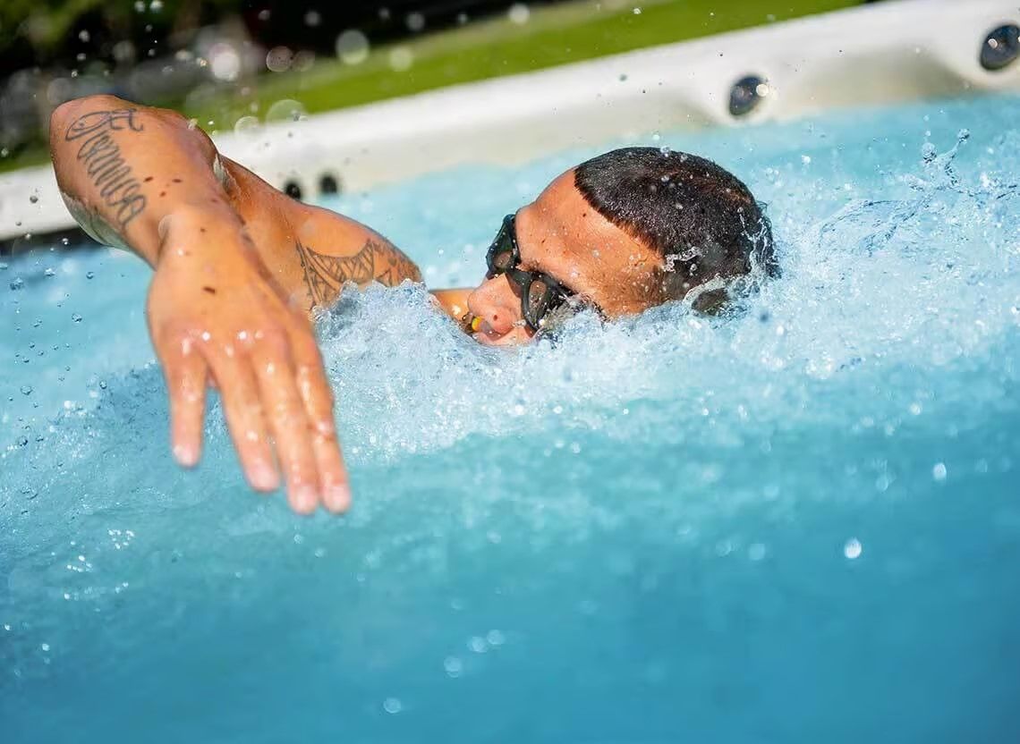 Un homme nageant le crawl dans une piscine, l'eau éclabousse autour de lui.
