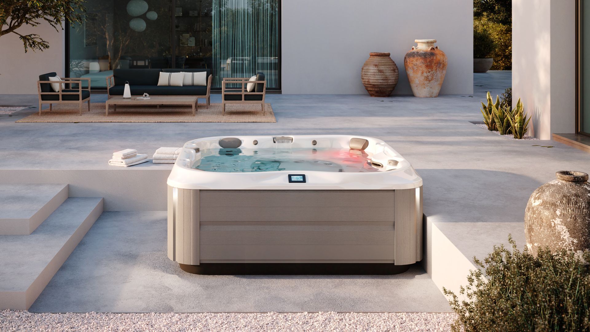 Jacuzzi sur une terrasse où une personne se détend. Aménagement extérieur avec mobilier moderne et plantes.