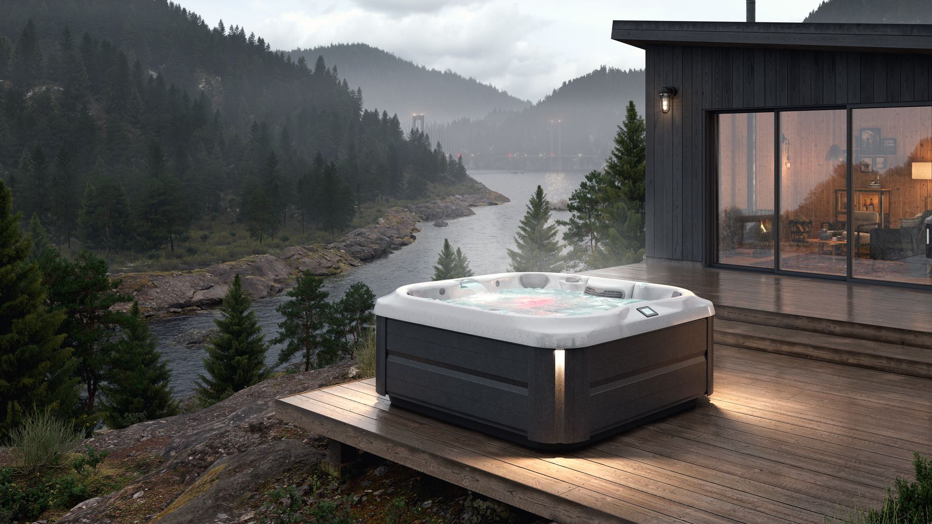 Jacuzzi sur une terrasse en bois surplombant un lac et des montagnes, illuminé au crépuscule.