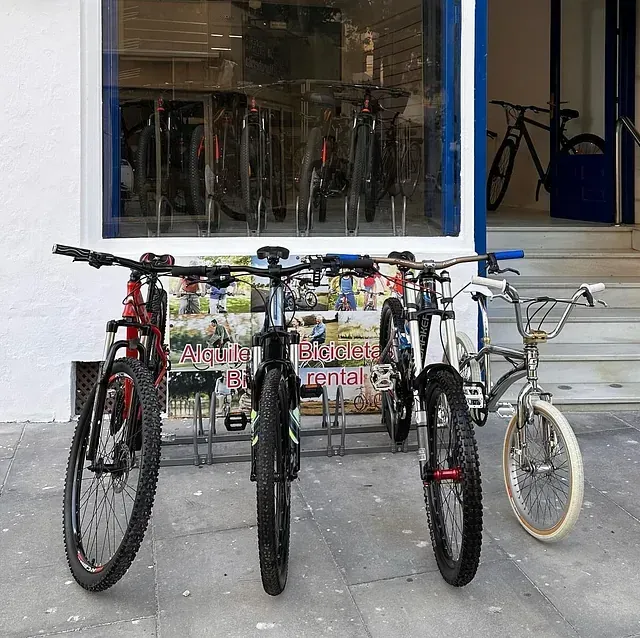 Tres bicicletas están estacionadas frente a una tienda que vende bicicletas.