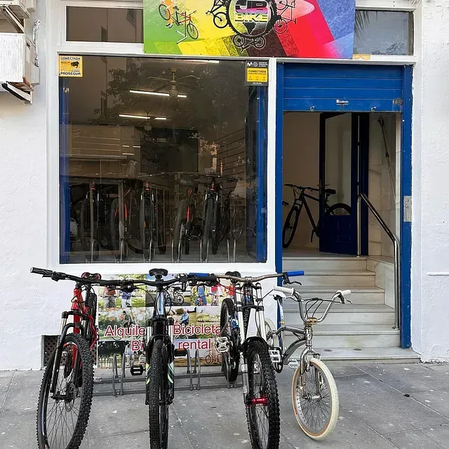 Varias bicicletas están aparcadas delante de una tienda de bicicletas.