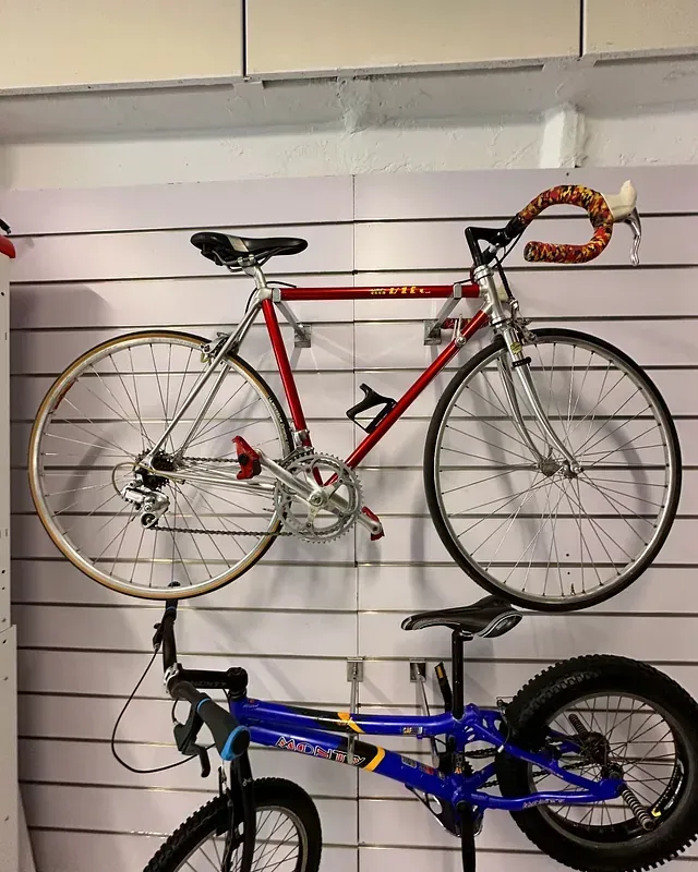Una bicicleta roja está colgada en una pared junto a una bicicleta azul.