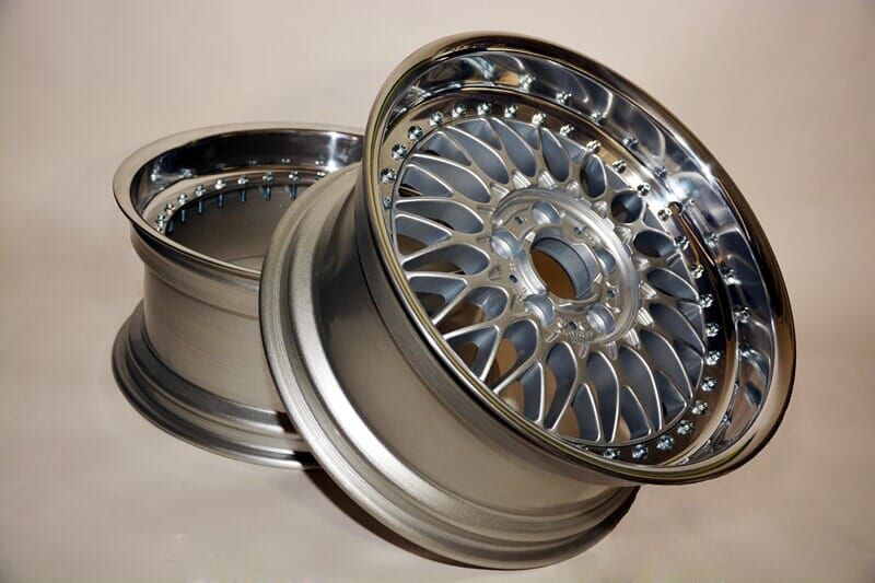 Duas jantes de liga leve prateadas com bordas polidas e design intrincado dos raios.