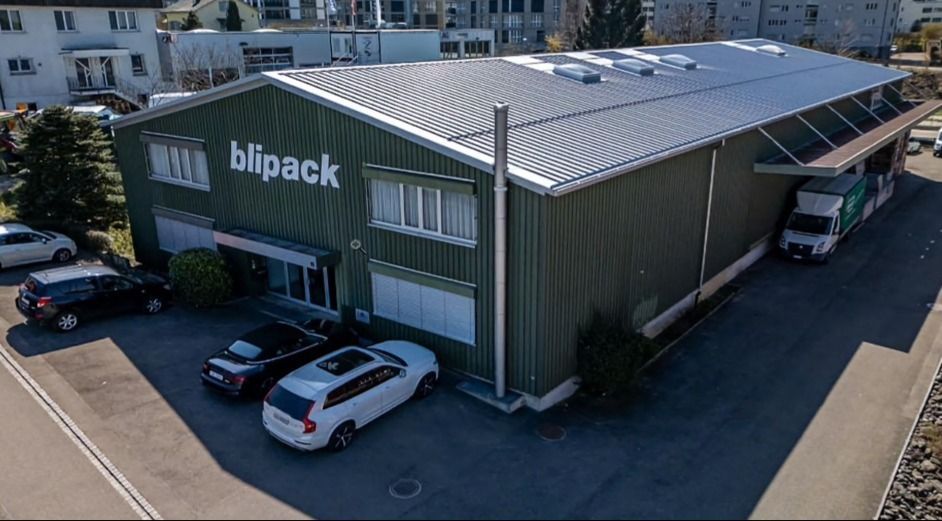 Dachdecker verlegt dunkelgraue Dachziegel an einem sonnigen Tag.