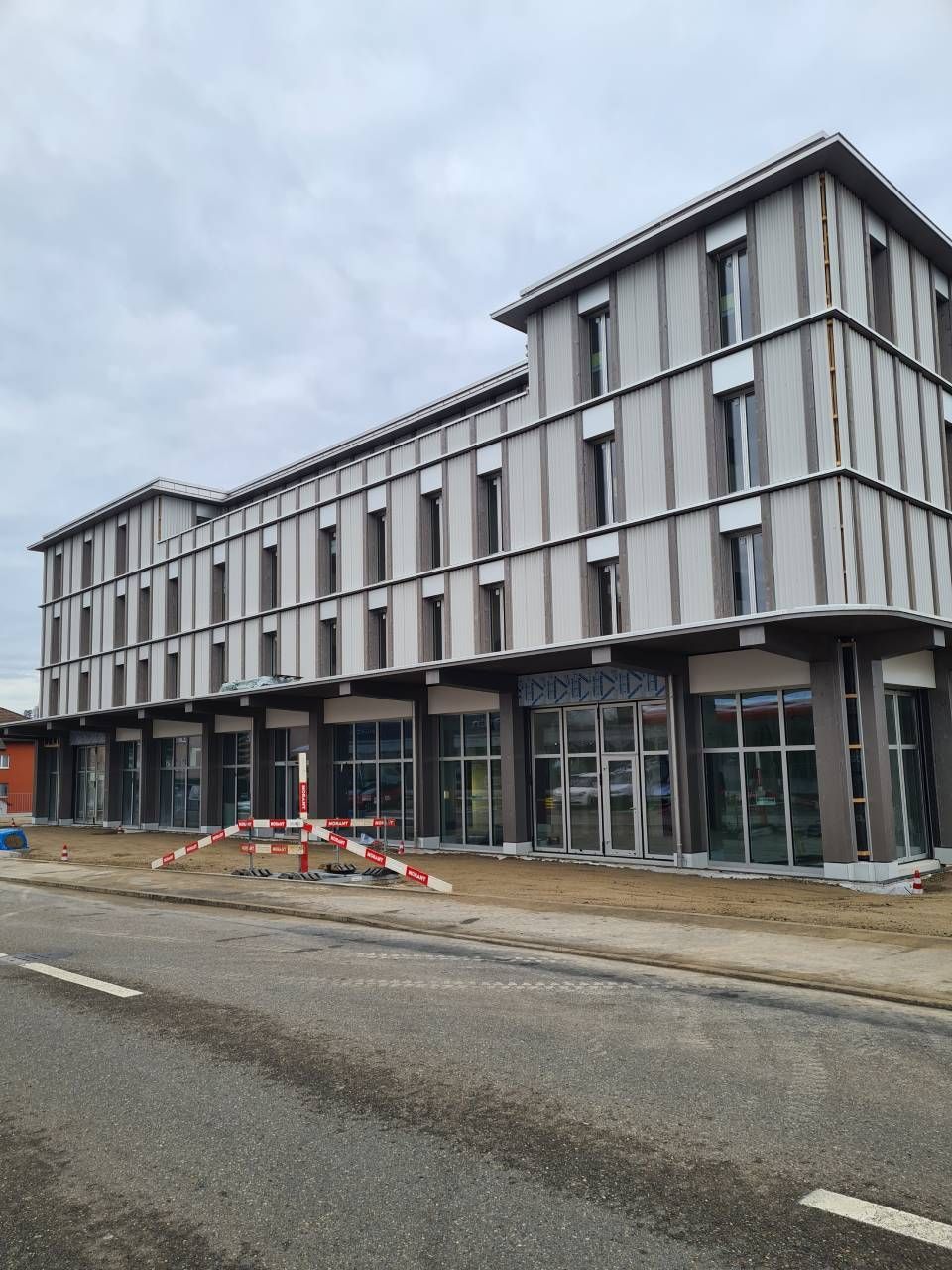 Dachdecker verlegt dunkelgraue Dachziegel an einem sonnigen Tag.