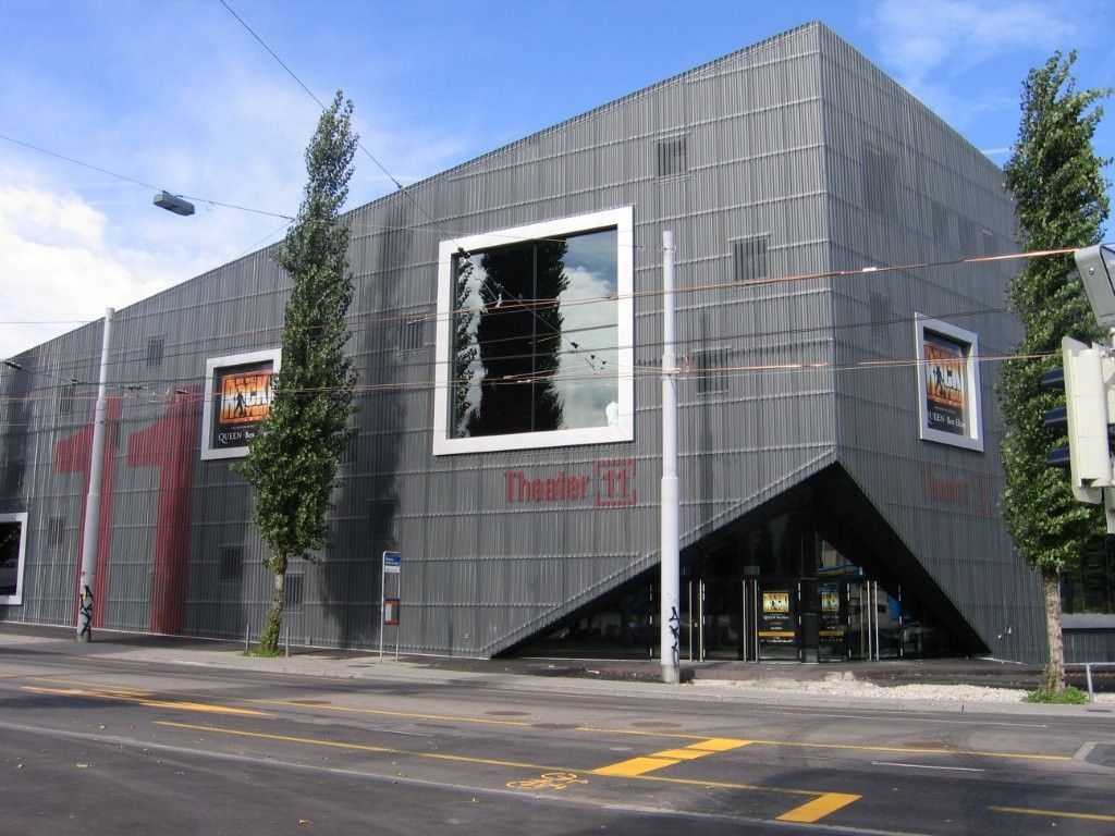 Zimmerrenovierung, blaue und graue Wände. Pappkartons, Leiter, Sofa und Pflanze. Sichtbare Deckenbalken.