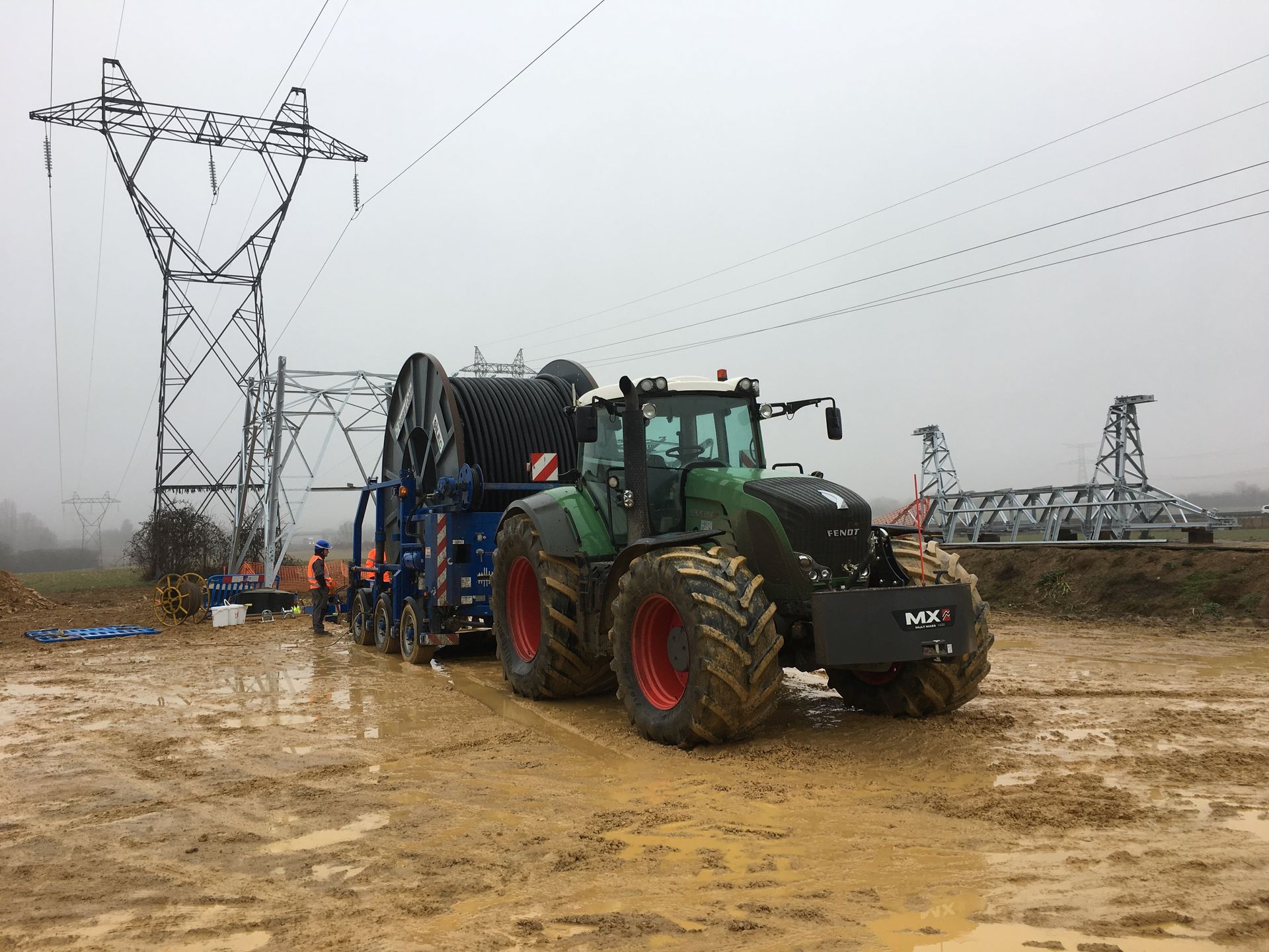 Engin près d'un pilonne électrique.