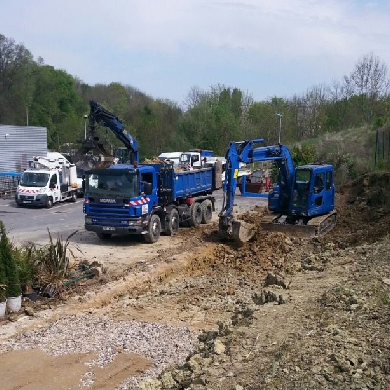 Engins de chantier bleus près d'une route.