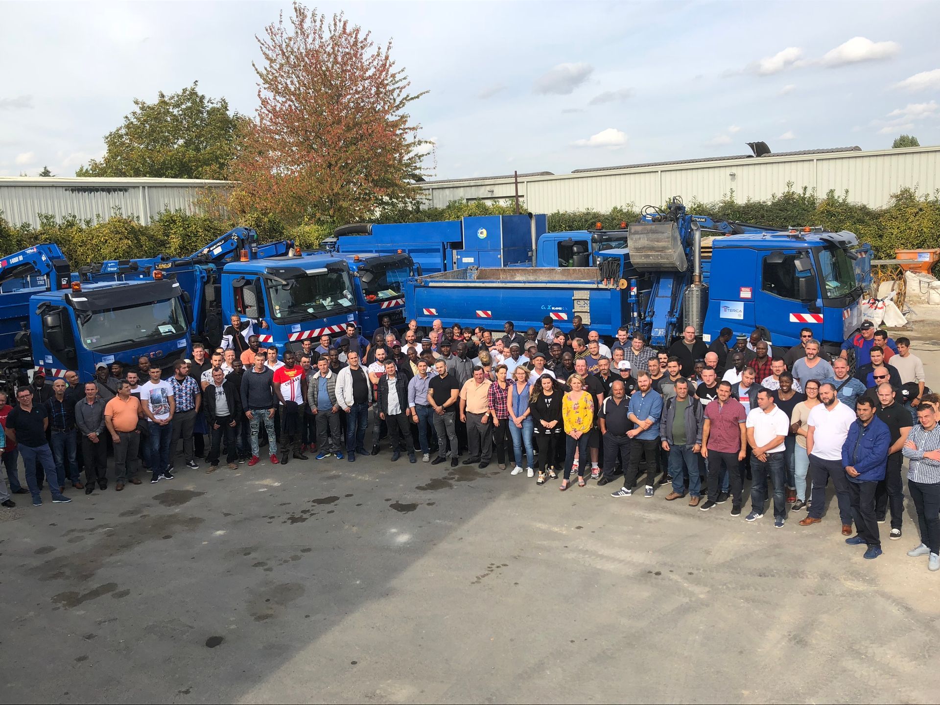 Ensemble de l'équipe de Terca posant devant des véhicules de l'entreprise.