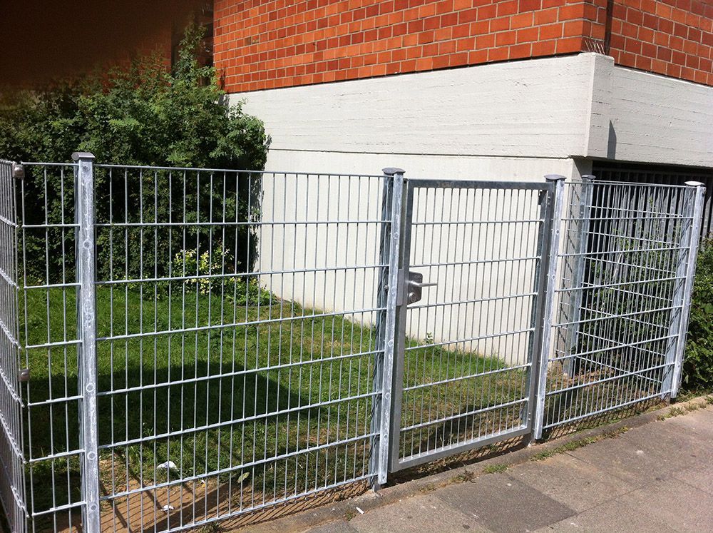Ein Zaun mit einem Tor vor einem Backsteingebäude