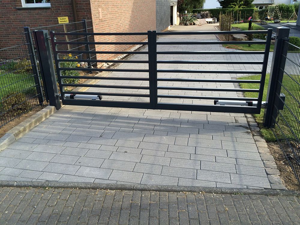 Eine gepflasterte Auffahrt mit einem offenen Tor