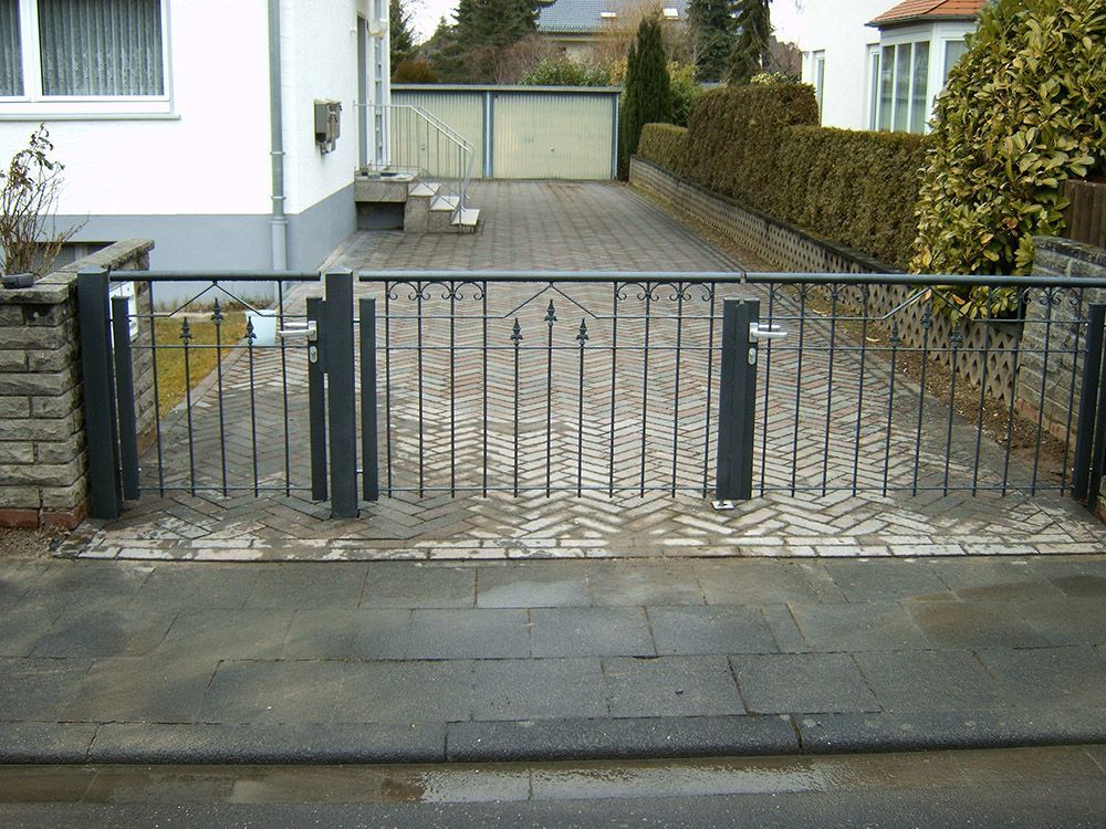 Ein Zaun mit einem Tor vor einem Haus