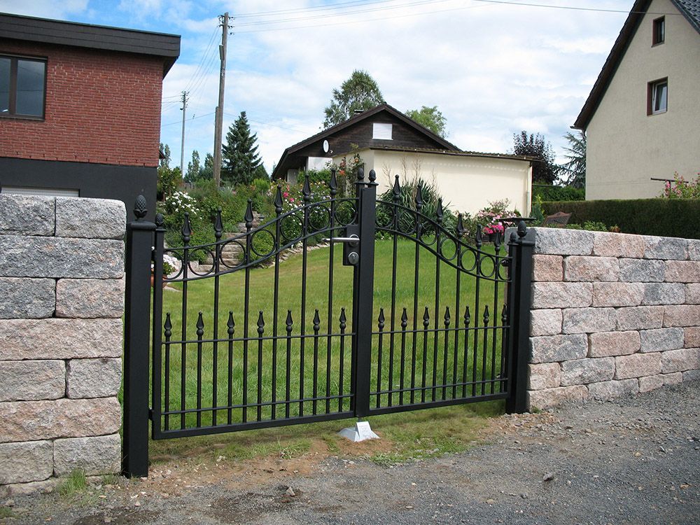 Eine Backsteinmauer mit einem schwarzen Tor davor