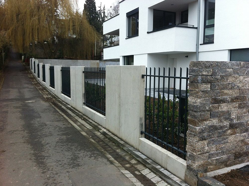 Ein weißes Gebäude mit einem schwarzen Zaun davor
