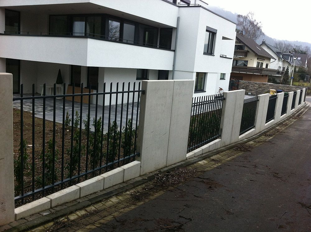 Ein weißes Gebäude mit einem schwarzen Zaun davor