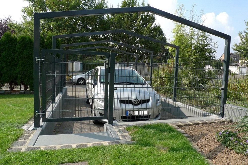 Ein Auto ist unter einem Zaun in einer Einfahrt geparkt