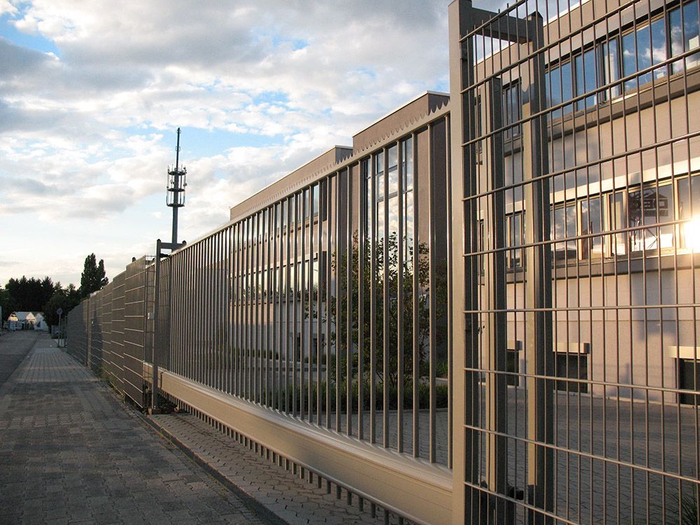 Ein Zaun mit Schiebetor vor einem Gebäude