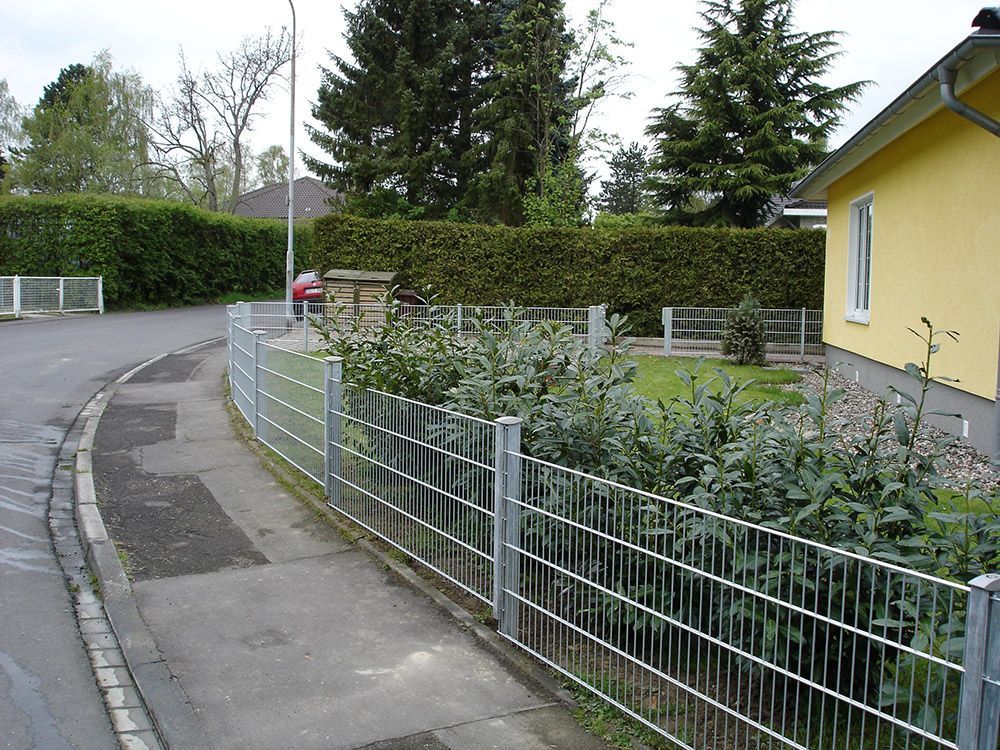 Ein gelbes Haus liegt hinter einem Maschendrahtzaun