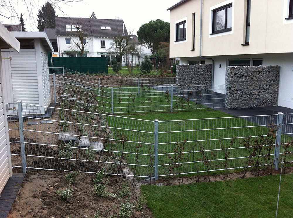 Ein Zaun umgibt einen üppigen grünen Hof vor einem Haus