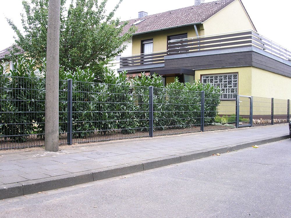 Ein gelbes Haus mit einem schwarzen Zaun davor