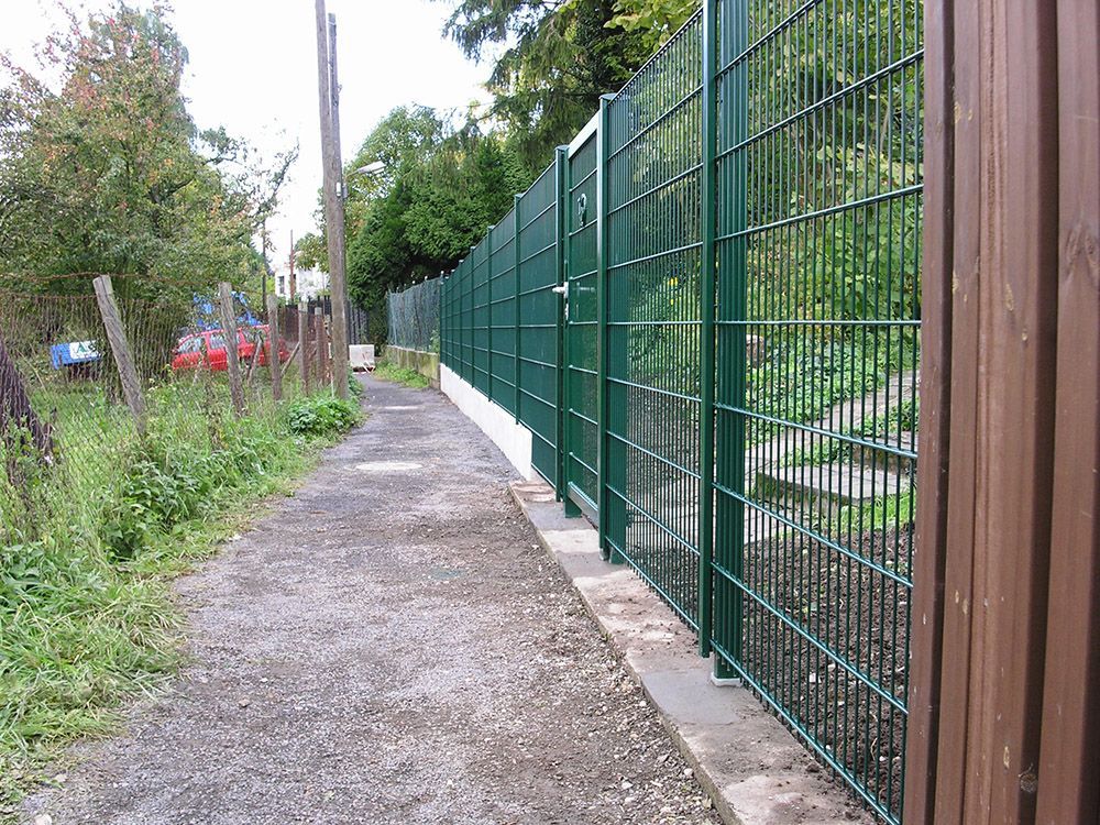 Ein Weg mit einem grünen Zaun an der Seite