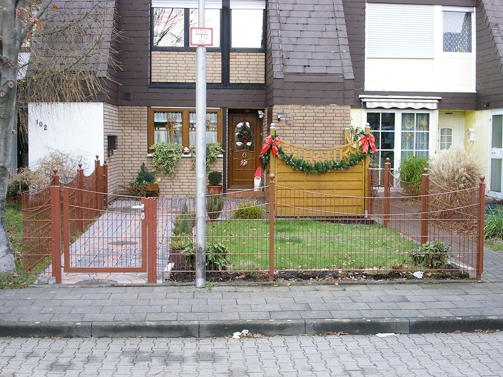 Ein Backsteinhaus mit einem Zaun und einem Schild mit der Aufschrift
