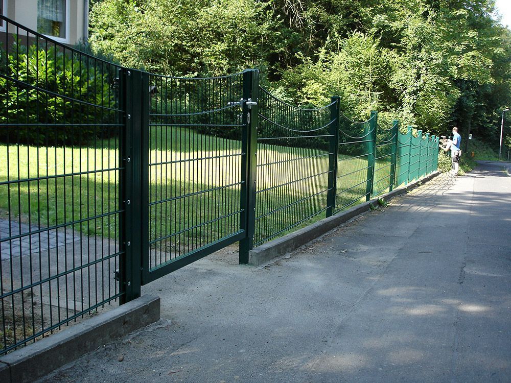Ein grüner Zaun entlang der Seite einer Straße