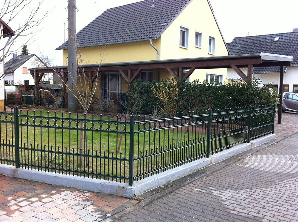 Ein gelbes Haus mit einem grünen Zaun davor