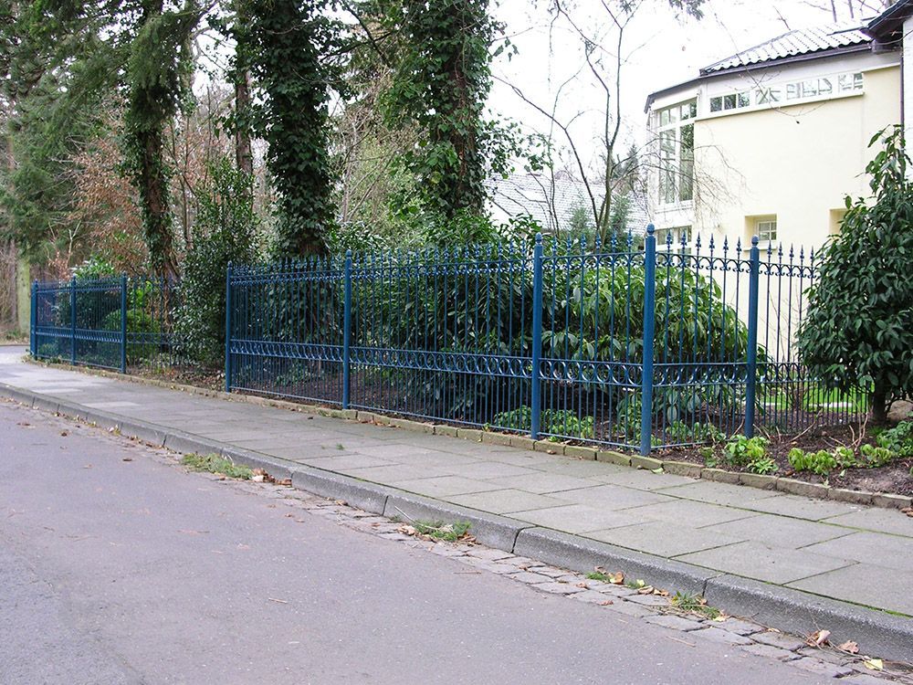 Ein blauer schmiedeeiserner Zaun am Straßenrand