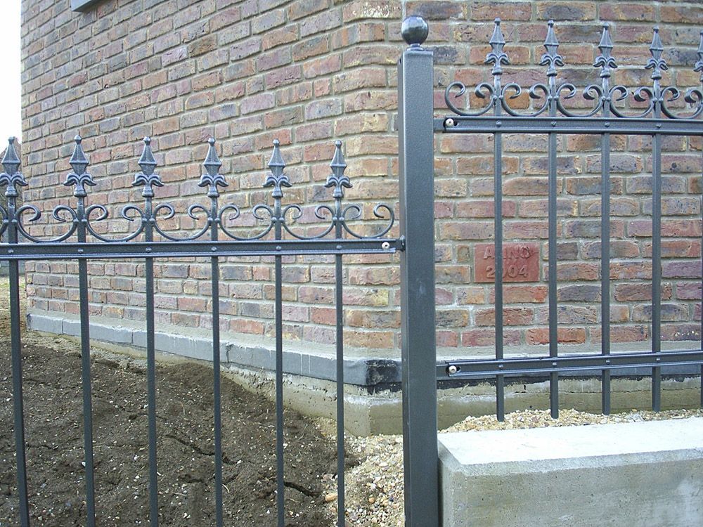 Eine Backsteinmauer mit einem schmiedeeisernen Zaun davor