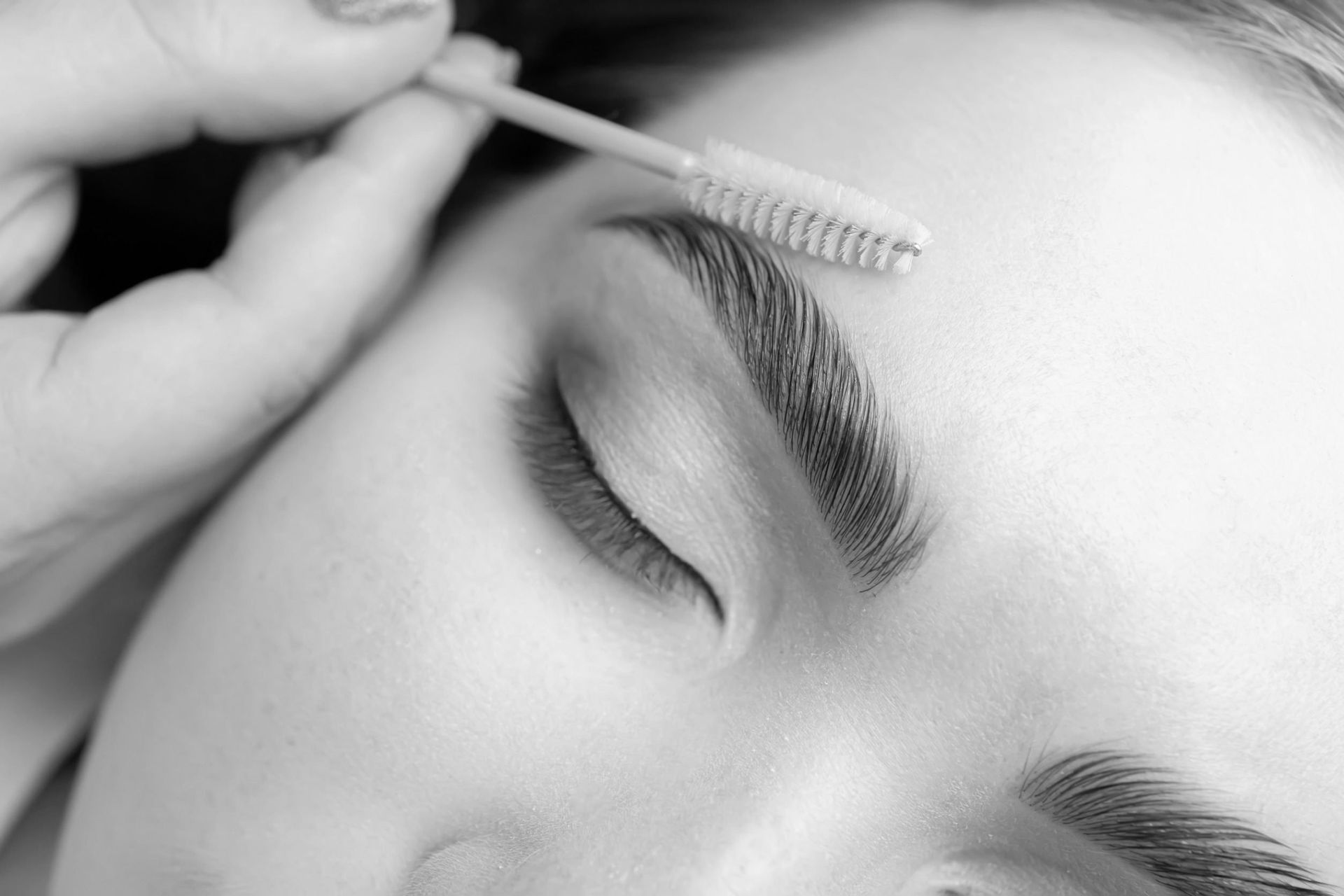 Una mujer se está haciendo las cejas en una foto en blanco y negro.