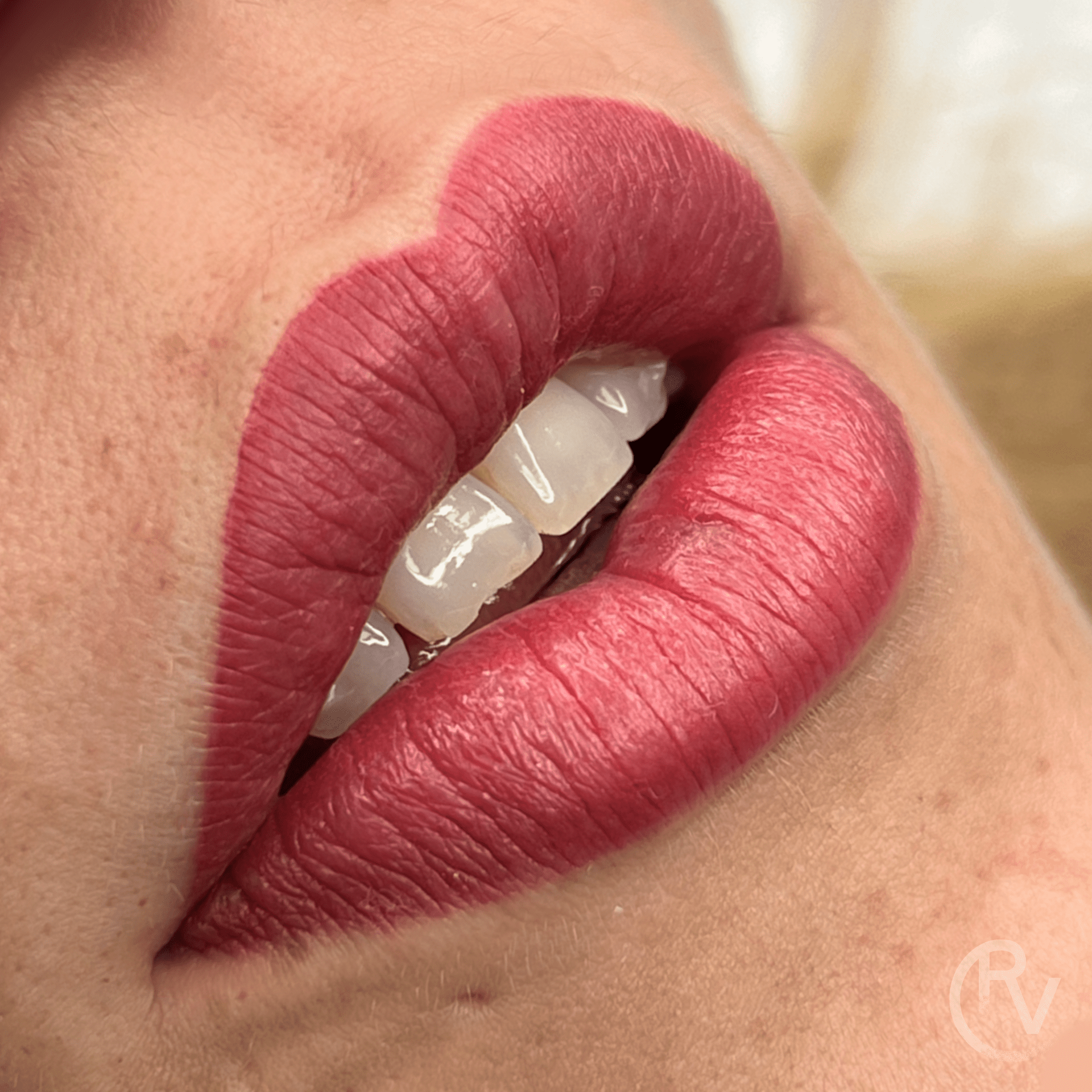 Un primer plano de los labios de una mujer con lápiz labial rojo y dientes blancos.