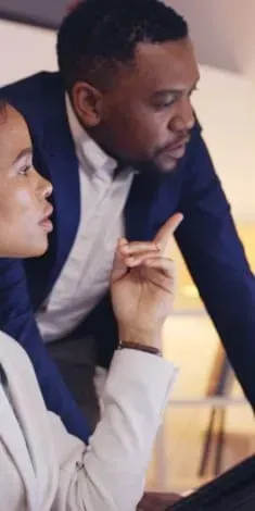 A man and a woman are looking at a laptop together.