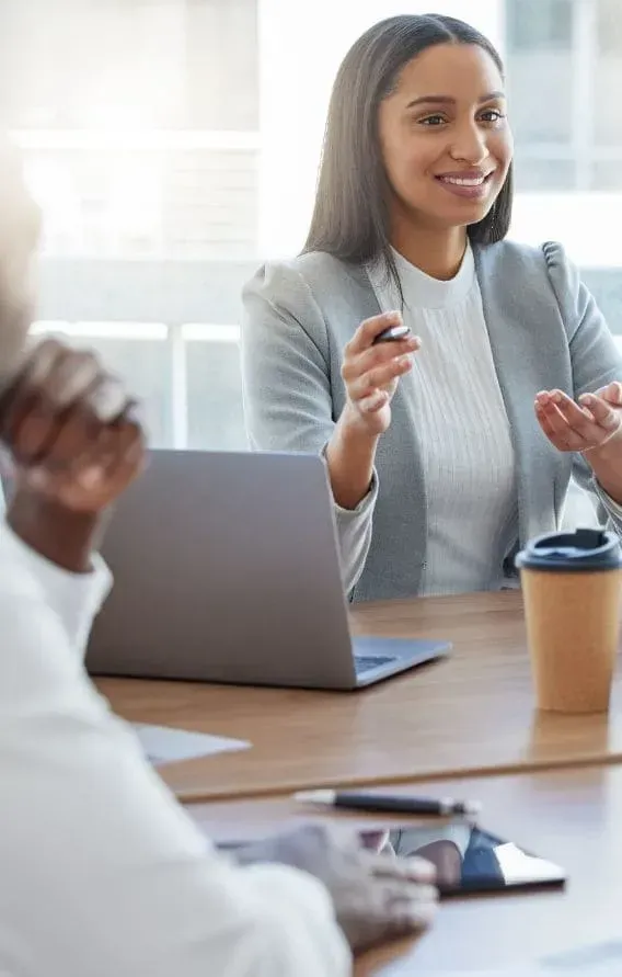 A woman is sitting at a table with a laptop and a cup of coffee.