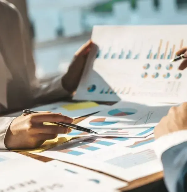 Two people are sitting at a table looking at charts and graphs.