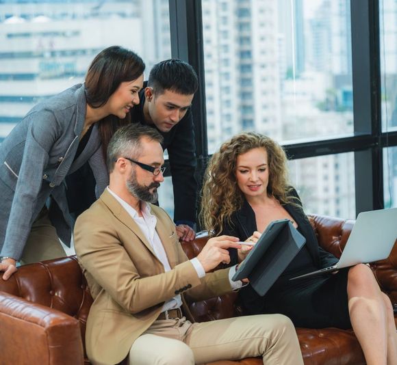 A group of people are sitting on a couch looking at a laptop.