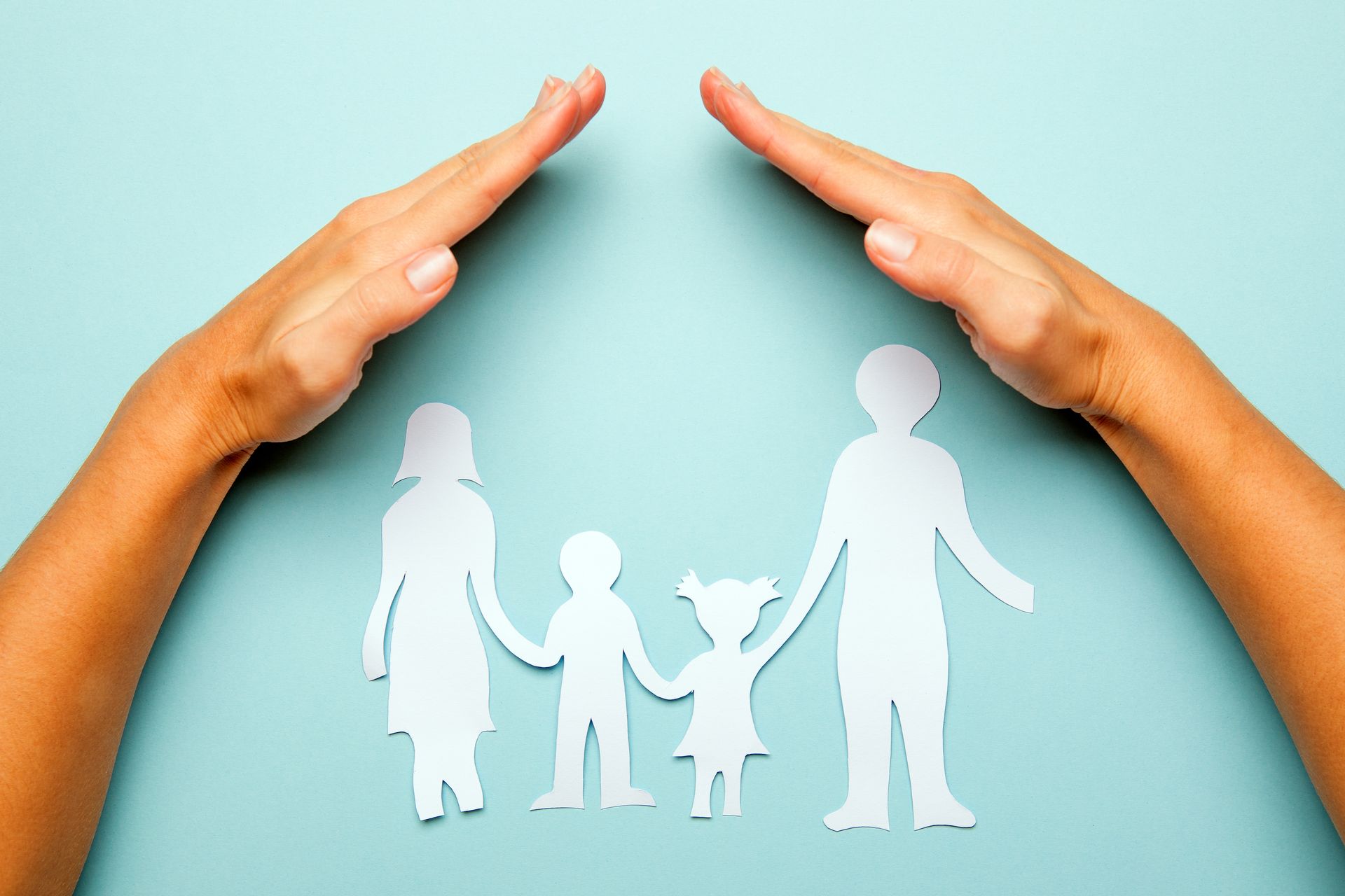 Mains protégeant une famille en papier