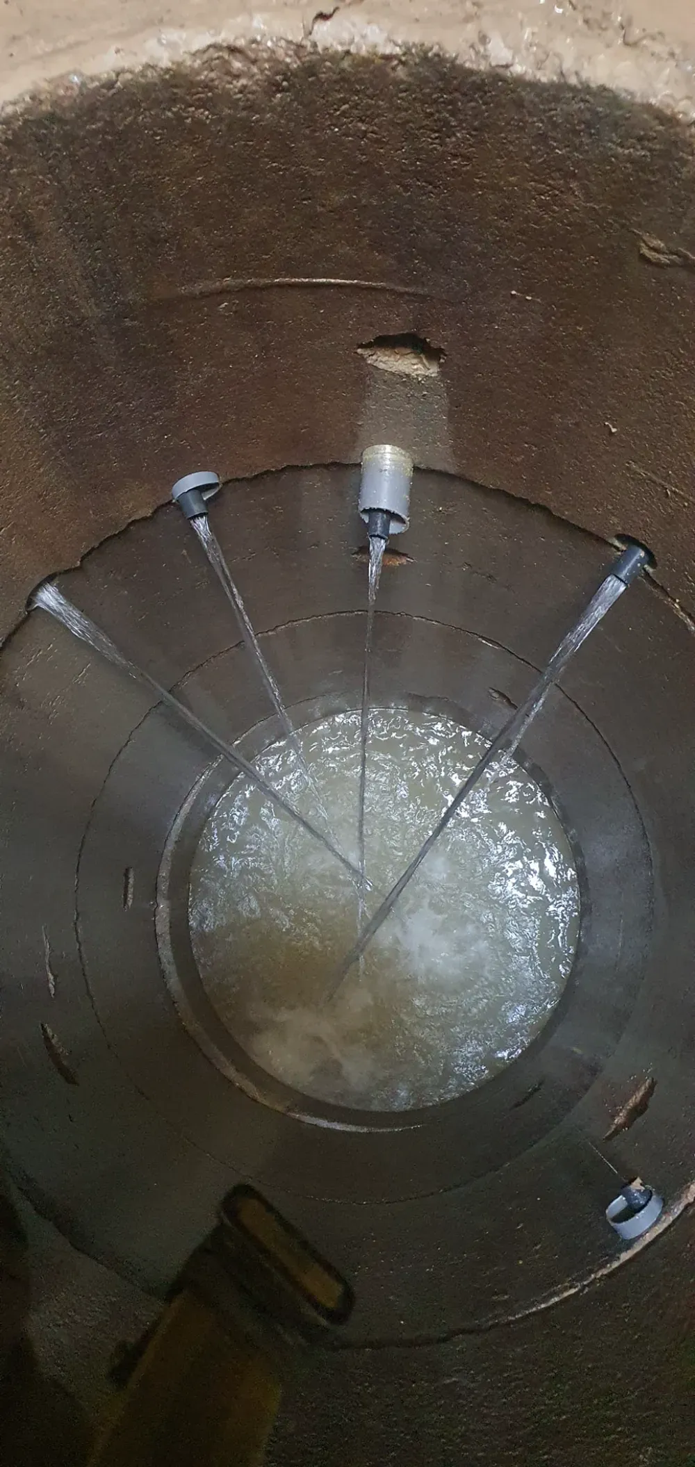 Hombre inspeccionando un pozo en el campo, al lado de una camioneta blanca bajo un cielo azul.