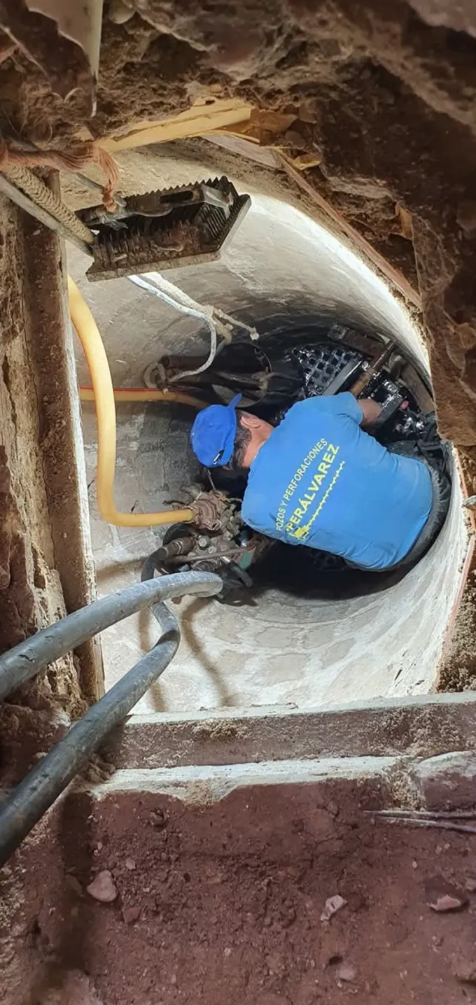Plataforma de perforación sobre un camión en una zona verde con tuberías azules. Día soleado.