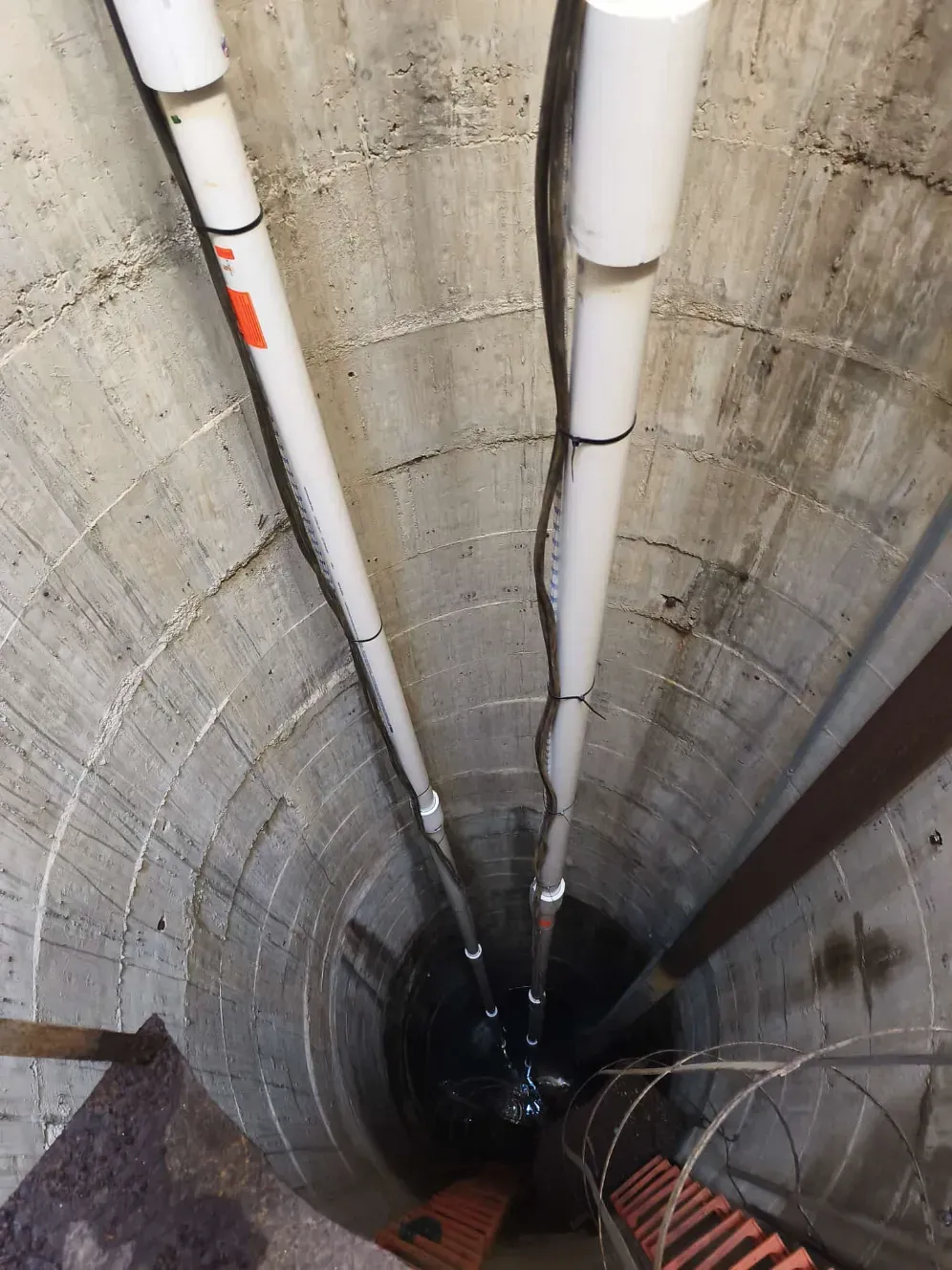 Mirando hacia abajo en un pozo cilíndrico, el agua burbujea y sale rociada desde un dispositivo central.