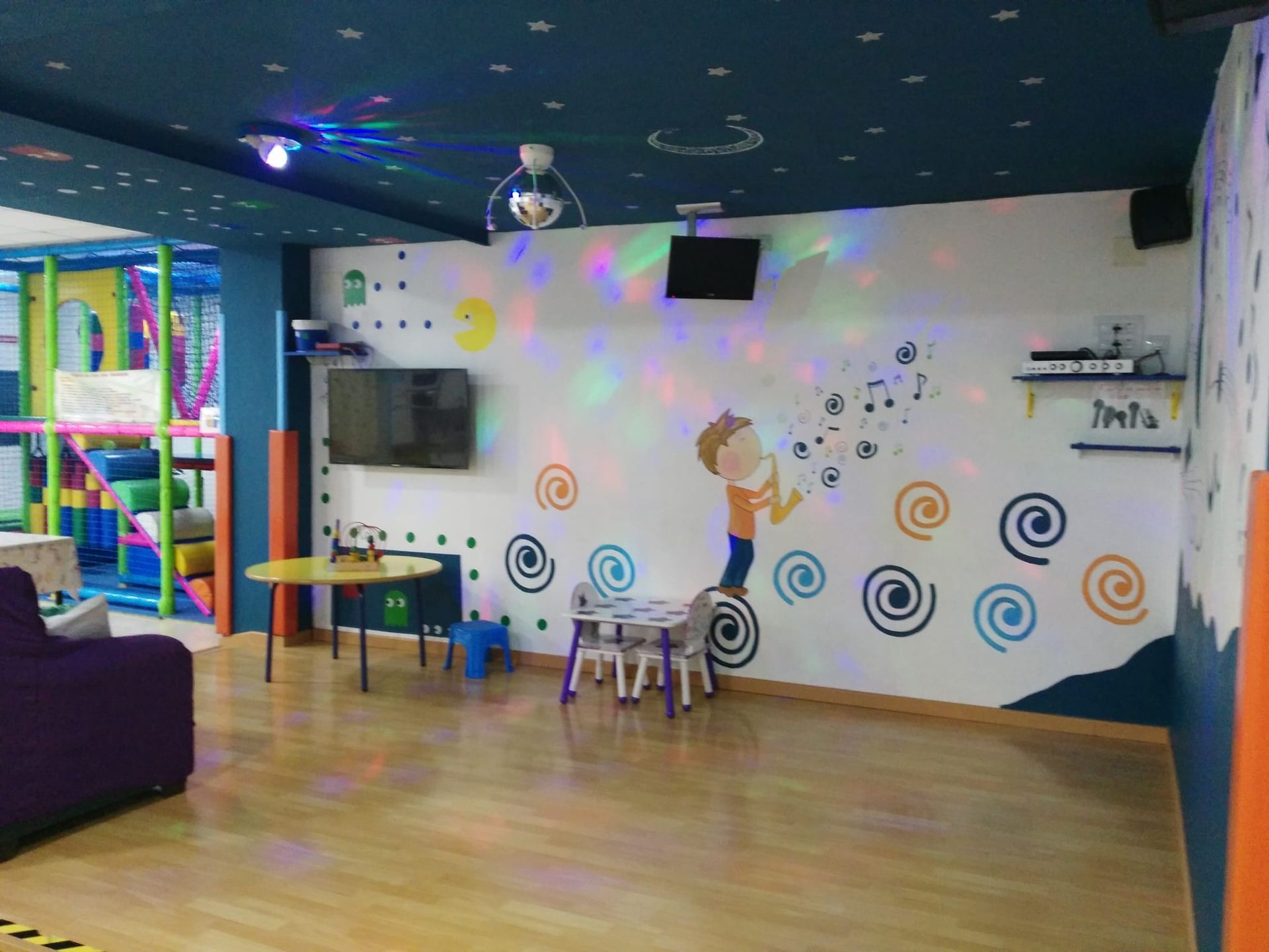 Una habitación con un sofá, una mesa, sillas y un televisor en la pared.