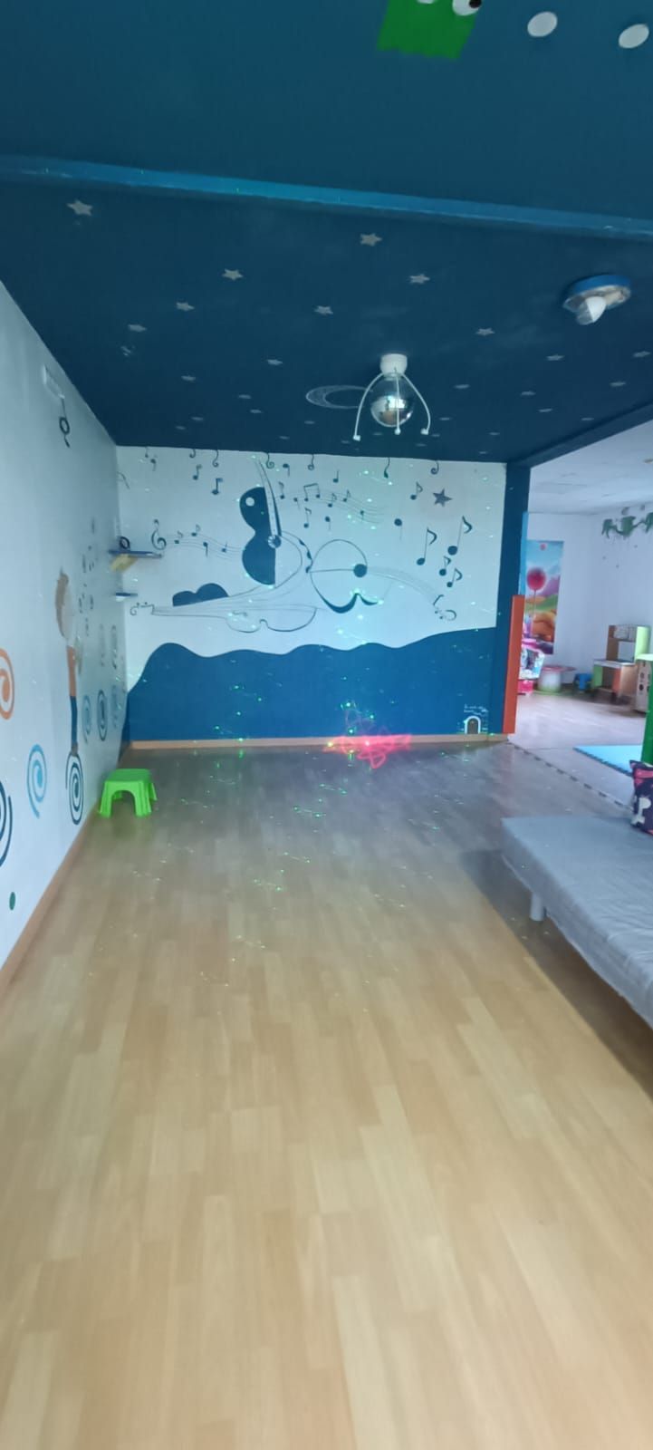 Una gran habitación vacía con suelo de madera y techo azul.