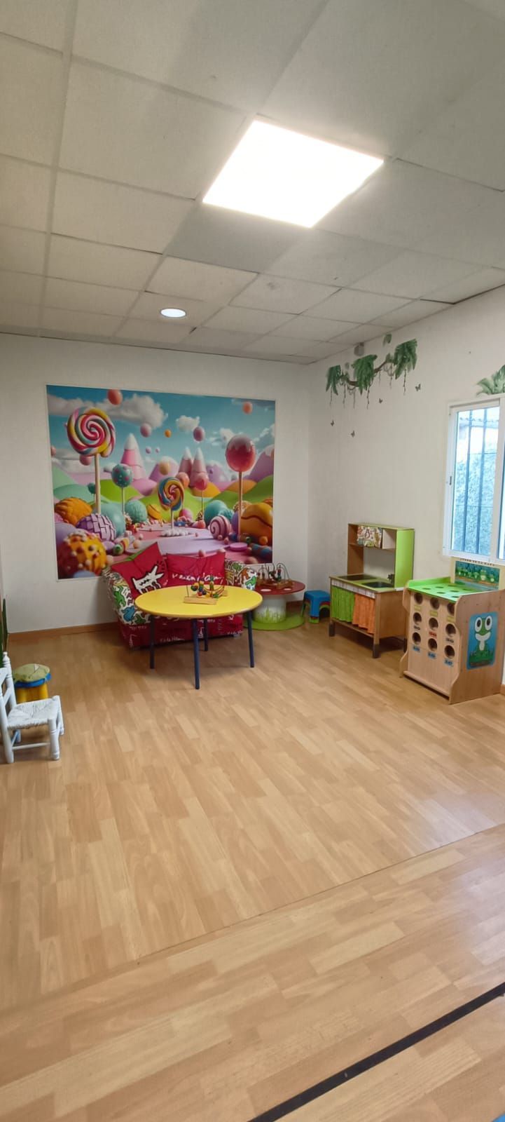 Una habitación con suelo de madera y una mesa y sillas en ella.