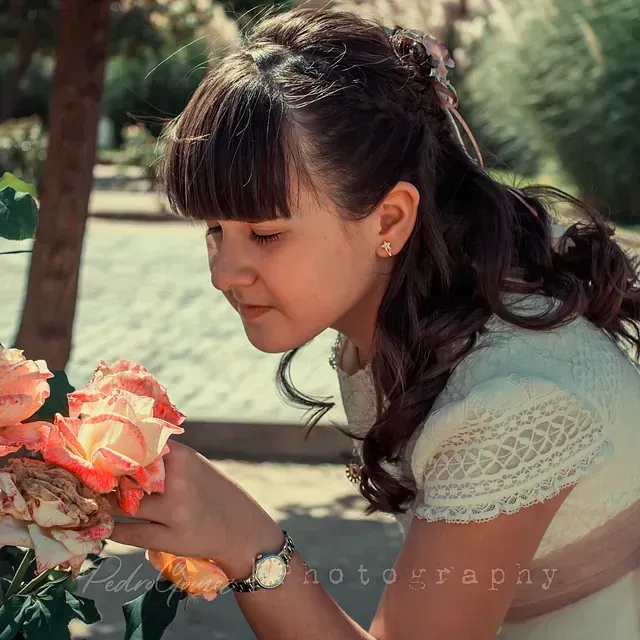 Una niña con un vestido blanco sostiene un ramo de flores.