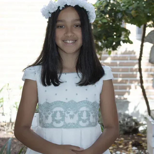 Una joven que lleva un vestido blanco y una corona de flores.