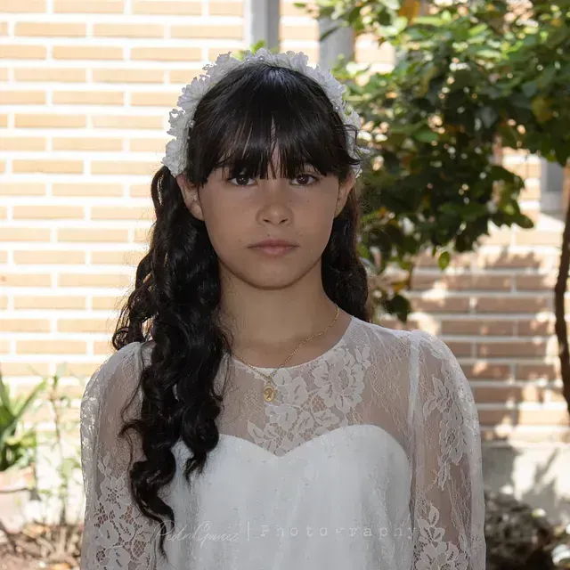 Una niña que lleva un top de encaje blanco y una diadema de flores.