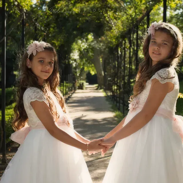 Dos niñas con vestidos blancos se toman de la mano
