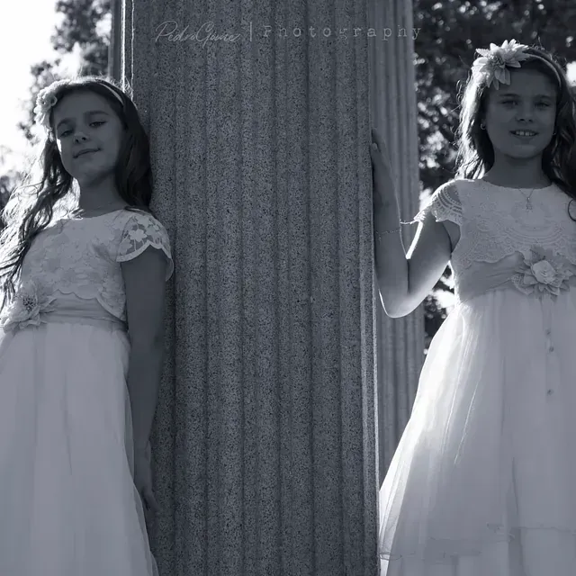 Dos niñas con vestidos blancos paradas una al lado de la otra